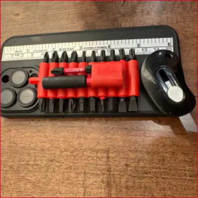 Screwdriver bit set with tape measure beside black case and box cutter for iPhone 14 Plus