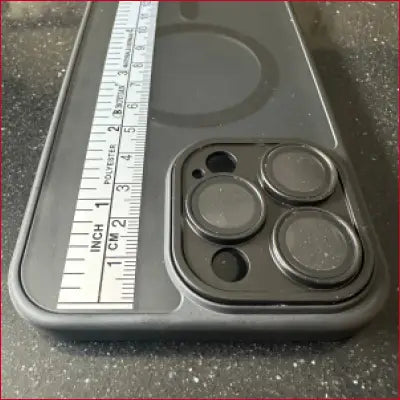 Black iPhone 15 Pro case with camera lens protection and silver ruler design