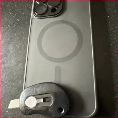 Gray iPhone 16 Plus Black Case with MagSafe and box cutter tool image