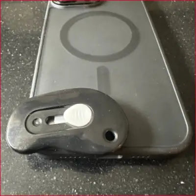 Black iPhone 16 Plus case with MagSafe and attached black box cutter grip