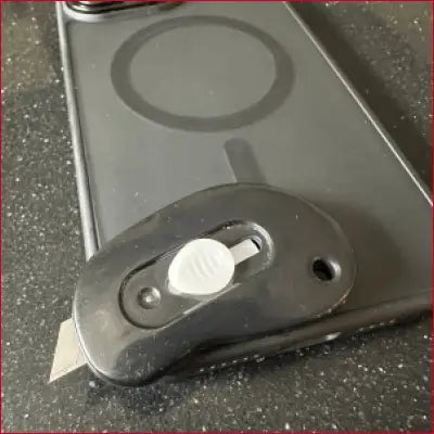 Black utility knife with exposed blade inside iPhone 16 Plus black case box cutter