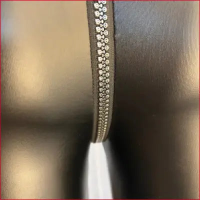Zipper with metallic teeth partially unzipped on Sexy Skull Teeth Crotch Zipper Faux Leather Leggings in Black
