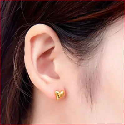 Curved Heart Solid 24k Gold Stud Earrings elegantly displayed on an earlobe