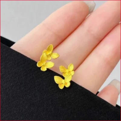 Yellow double butterfly stud earrings resting on a person’s palm for secure shipping