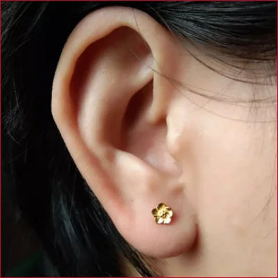 Gold flower-shaped stud earring worn in earlobe from 24K Solid Gold collection