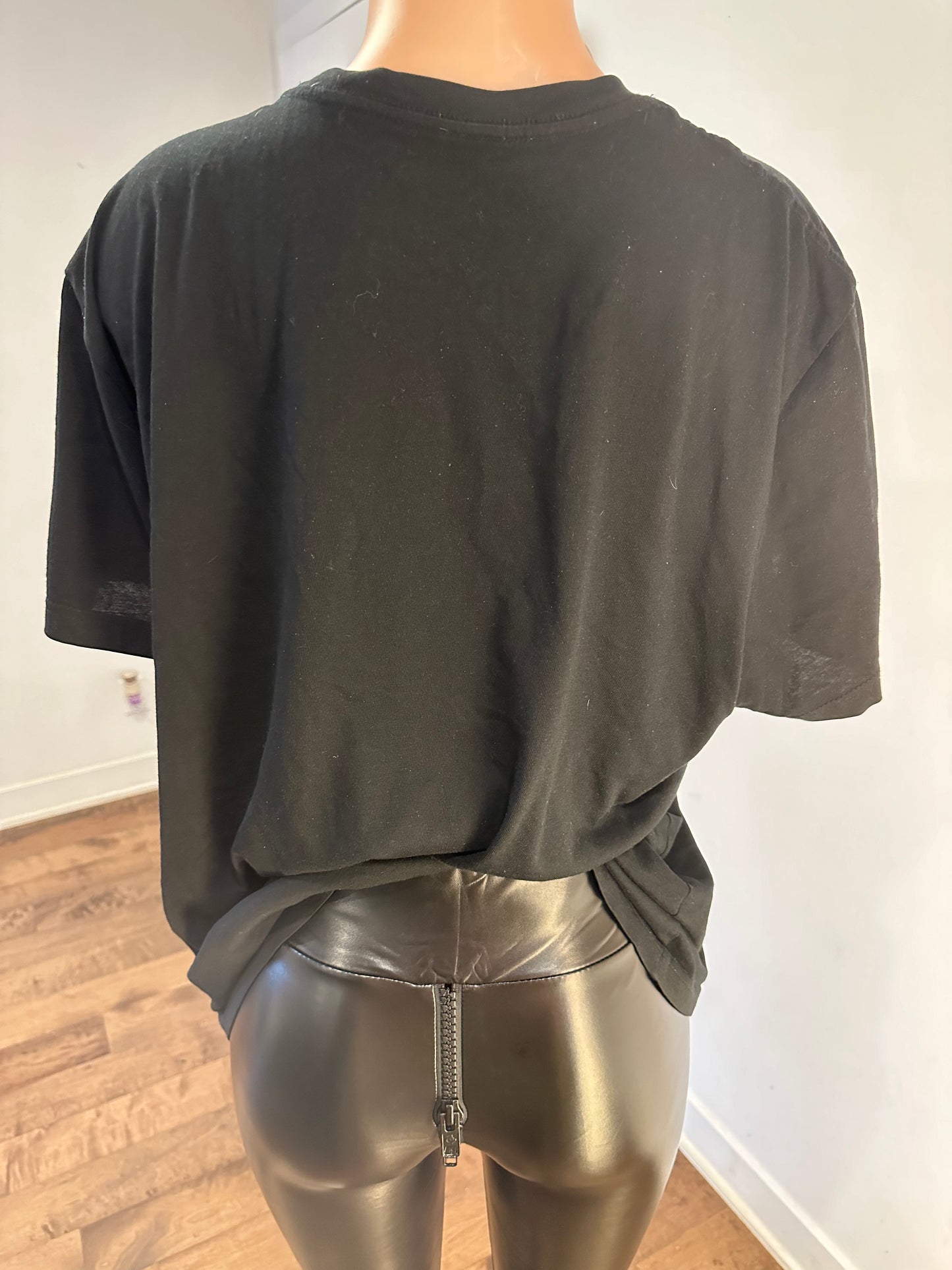 Person in a handmade black crew neck t-shirt and shiny metallic leggings