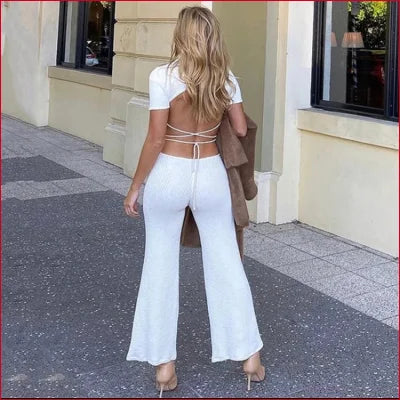 Woman in a white turtleneck cutout knitted crop top and wide-leg pants with open back