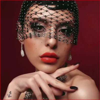 Woman in ornate beaded birdcage bridal veil hair hoop with dramatic makeup on red background