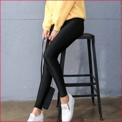 Person seated on stool wearing shiny black spandex disco leggings for a stunning look