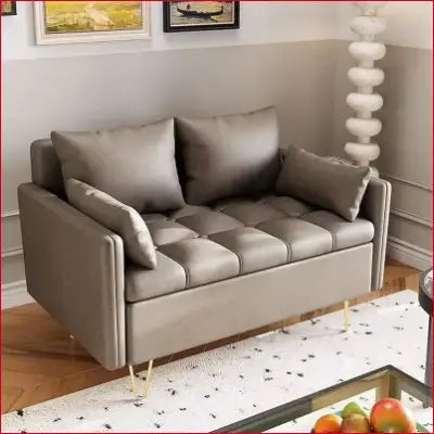 Gray tufted loveseat with gold legs, a modern design in faux leather love seats