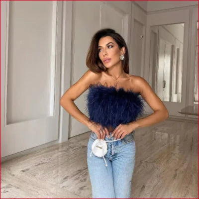 Woman in a navy blue faux feather crop top with light blue jeans showcasing style