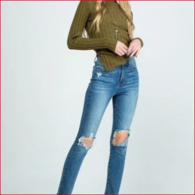 Pair of destroyed skinny denim jeans with clean hem and olive green top styled together