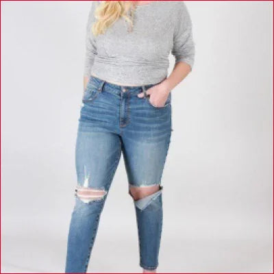 Distressed blue super stretchy skinny jeans with rips worn by a person in a gray top