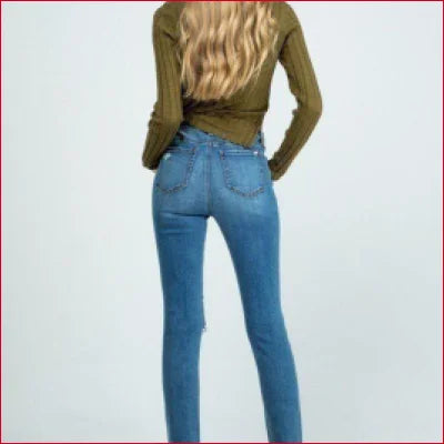 Blue denim jeans with clean hem on a person in a green top showcasing destroyed skinny style