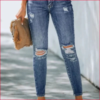 Distressed high rise skinny jeans with ripped knees paired with a tan handbag