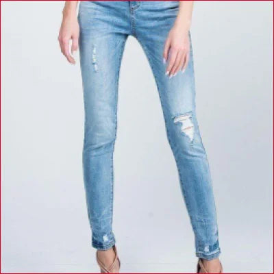 Pair of medium-light wash distressed skinny jeans with rips and frayed hems