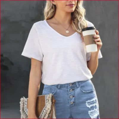 Woman wearing high waist denim shorts with frayed hem holding a coffee cup