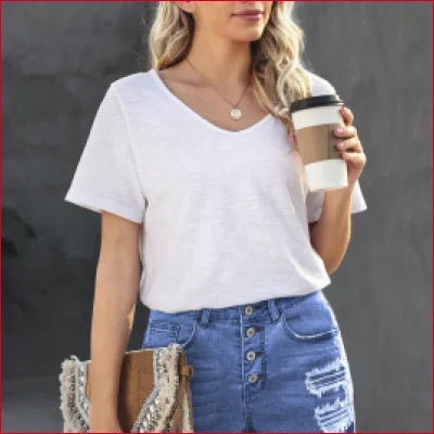 Woman in white t-shirt and denim skirt enjoying coffee, showcasing high waist denim shorts