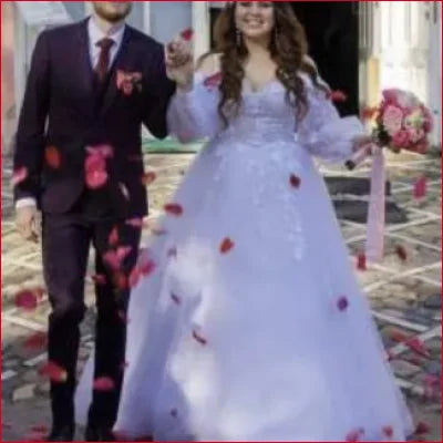 Wedding couple in gorgeous lace off shoulder bridal gown surrounded by rose petals