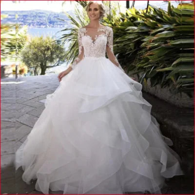 Ornate white wedding gown with tulle lace sleeves and voluminous layered skirt