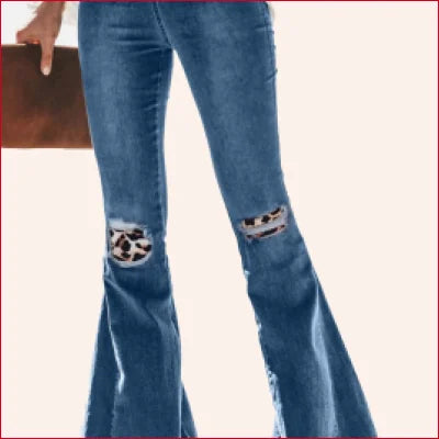 Pair of flared blue jeans with ripped knees revealing cow print, perfect for vintage leopard patchwork style