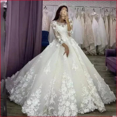 Ornate white long sleeves wedding dress with lace appliqués and voluminous ball gown skirt