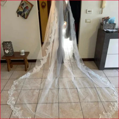 Long Tulle Bridal Comb Veil with lace trim spread on tiled floor for elegant weddings