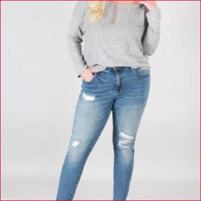 Distressed blue jeans in medium wash worn with a gray sweater for a vintage look