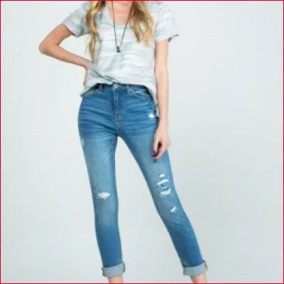 Person in stretchy denim jeans with distressed details and rolled cuffs, light t-shirt