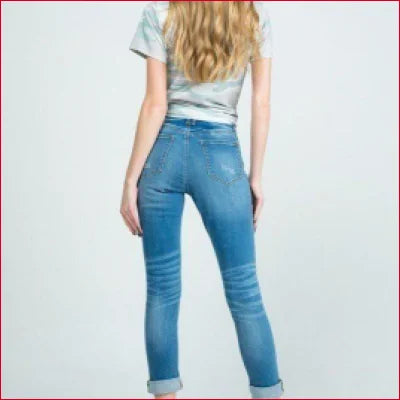 Person with long blonde hair wearing stretchy denim jeans with distressed details