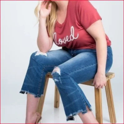 Woman in red t-shirt and ripped blue jeans showcasing Vintage Kick Flare Jeans with ankle length distressed hem