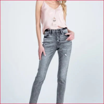 Pair of distressed grey wash button fly skinny jeans styled with a pale pink camisole