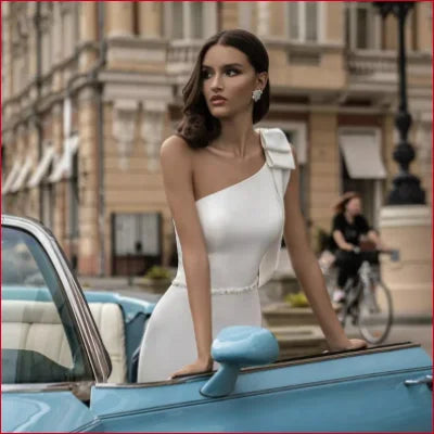 Woman in a white shoulder wedding dress next to a classic blue vintage car