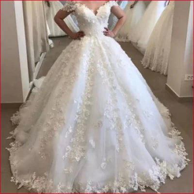 Ornate white off shoulder wedding dress with voluminous skirt and floral appliqués