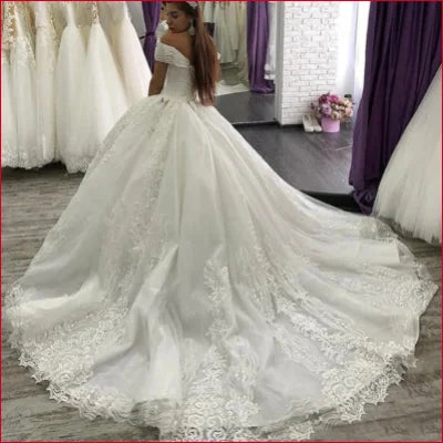 Ornate white wedding dress with lace detailing and voluminous skirt, off shoulder design