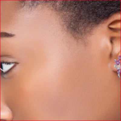 Close-up of a person’s eye and ear showcasing Sterling Silver Flowers Stud Earrings with Plum Zircon