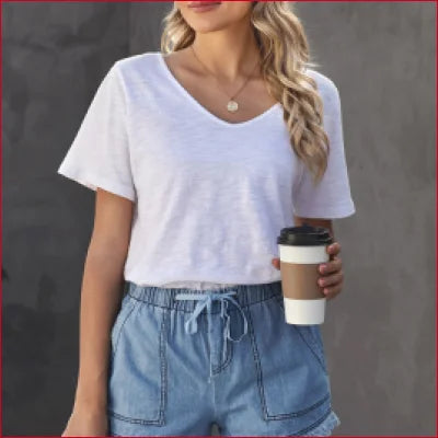 Woman in casual denim shorts holding a takeaway coffee cup, showcasing chic style