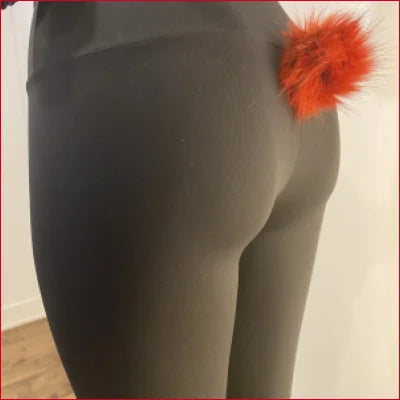 Mannequin lower body in black spandex leggings with red pompon and orange fluffy tail