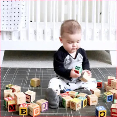 Baby playing with alphabet blocks on a Premium Stylish Foam Play Mat in black linen