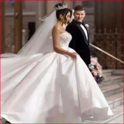 Bride in a princess satin wedding dress with groom in black tuxedo, showcasing elegance