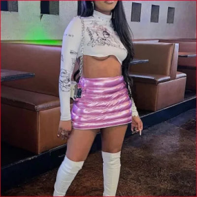 Woman in cropped white top and shiny pink Y2K short ribbed quilted skirt with boots