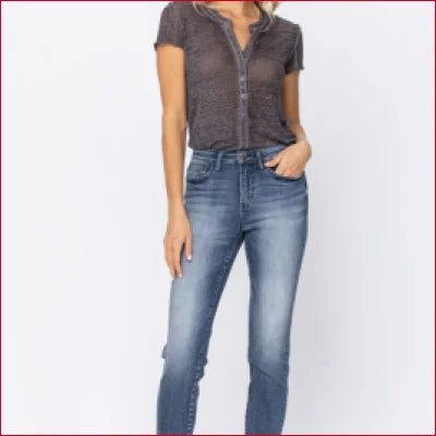 Woman in gray button-up shirt showcasing high waist raw hem jeans for a stylish fit