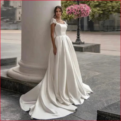 Elegant white wedding dress with cap sleeves, flowing train, and crotch zipper detail