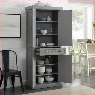 Gray pantry cabinet with open doors and drawer in Distressed Gray and Gold finish