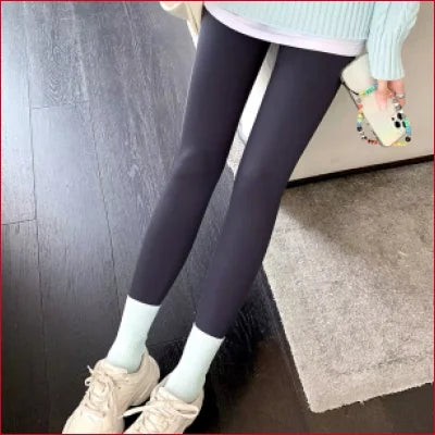 Pair of legs in sexy thermal leggings, white socks, and beige sneakers for women