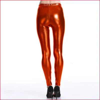 Shiny metallic orange disco pants styled with black high heels for a trendy look