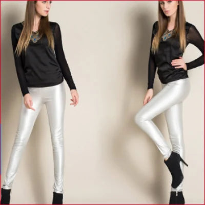 Two women in black tops and shiny silver high waist leather leggings showcasing style