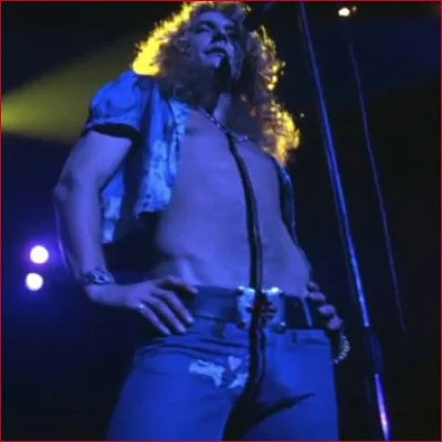 Rock singer with curly hair wearing stained women’s pencil blue jeans on stage