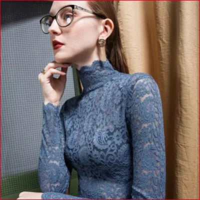 Woman in a blue lace Victorian turtleneck long sleeve blouse with round glasses