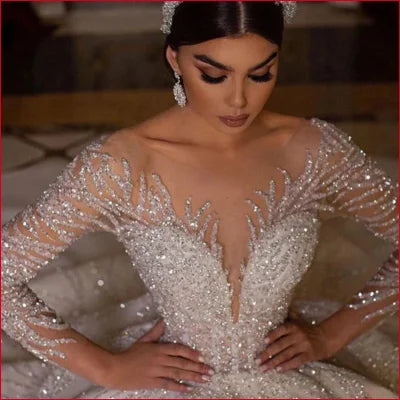 Ornate sexy wedding dress featuring intricate beadwork and sheer long sleeves